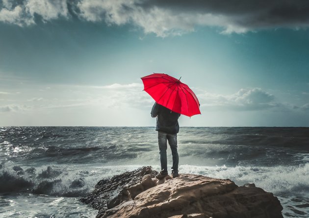 firefly_young_man_with_red_umbrella_looking_towards_the_horizon_on_a_rock_in_the_open_stormy_sea_318.jpg